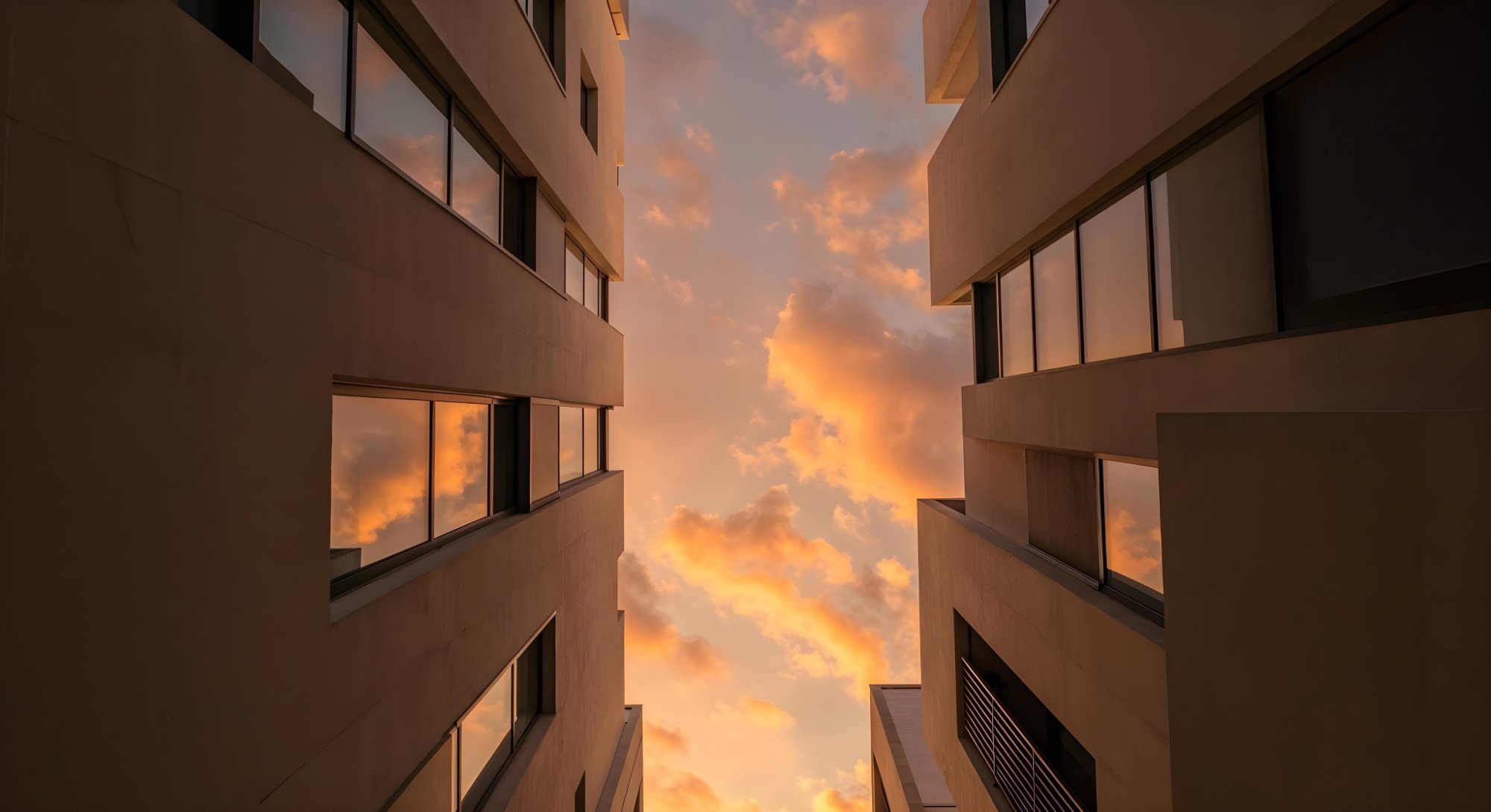 Vista en contrapicado entre dos edificios residenciales de Pamplona con el cielo del atardecer entre ellos